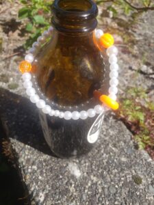 hand crated pearl bracelet on a brown beer bottle